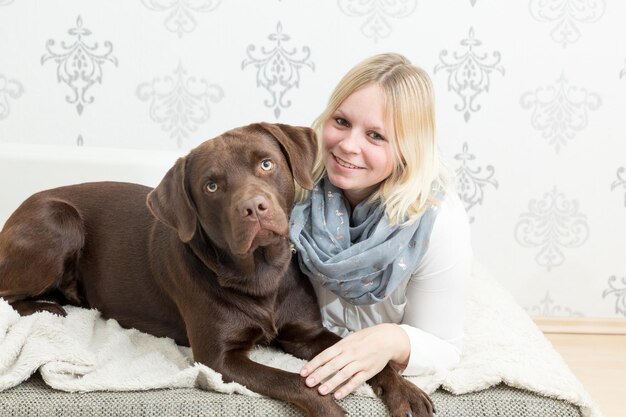 Zdjęcie portret uśmiechniętej kobiety z psem odpoczywającym w łóżku w domu