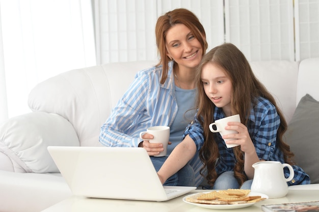 Portret uśmiechniętej matki i córki z laptopem w domu