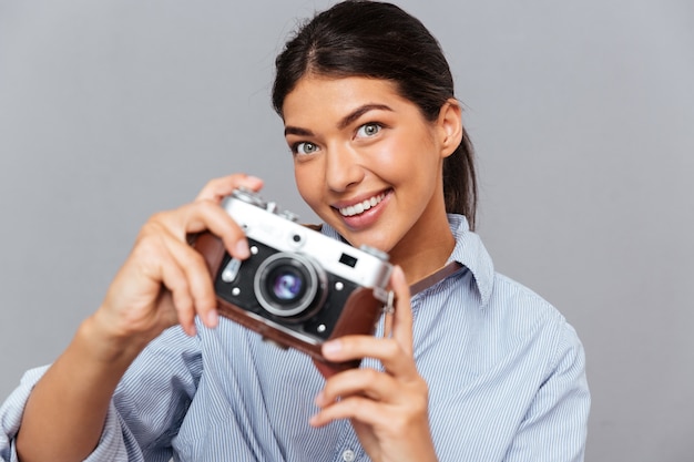 Portret Uśmiechniętej Młodej Brunetki Trzymającej Zdjęcie Z Przodu Izolowane Na Szarej ścianie