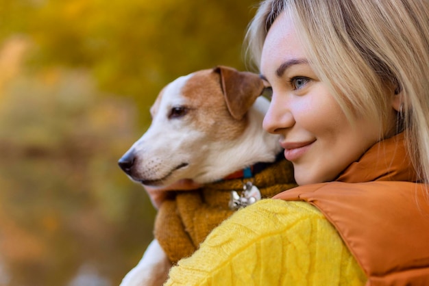 Portret uśmiechniętej młodej kobiety całującej psa na polu Miłośniczka psów stylowa dziewczyna przytulająca psa podczas chodzenia Koncepcja przyjaźni ze zwierzętami