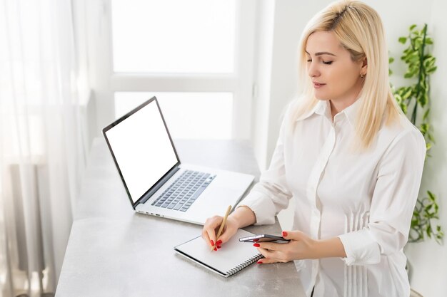 Portret Uśmiechniętej Młodej Kobiety Korzystającej Z Laptopa I Telefonu Komórkowego