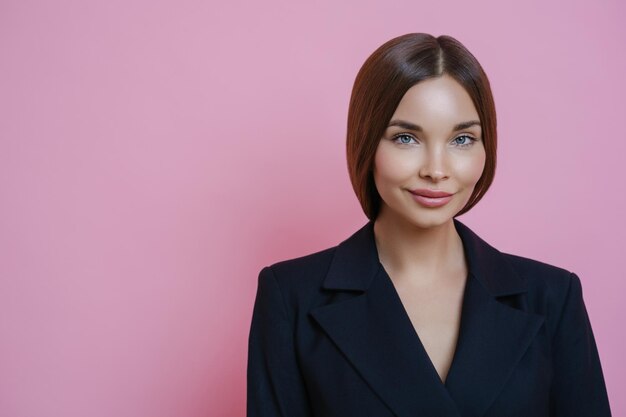 Portret uśmiechniętej młodej kobiety na różowym tle