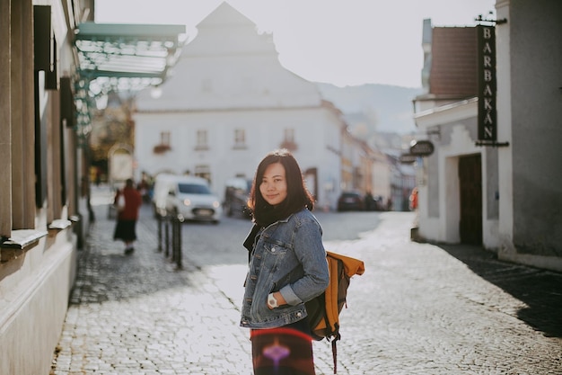 Portret uśmiechniętej młodej kobiety w mieście na tle nieba
