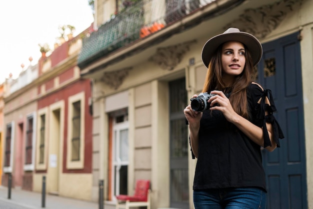 Portret uśmiechniętej młodej kobiety z aparatem na zewnątrz