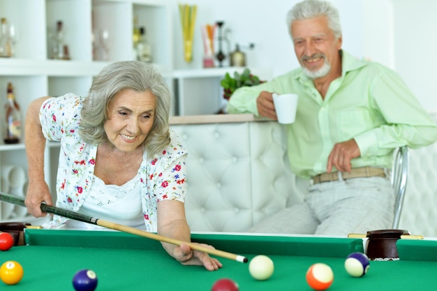 Portret uśmiechniętej pary seniorów grającej razem w bilard