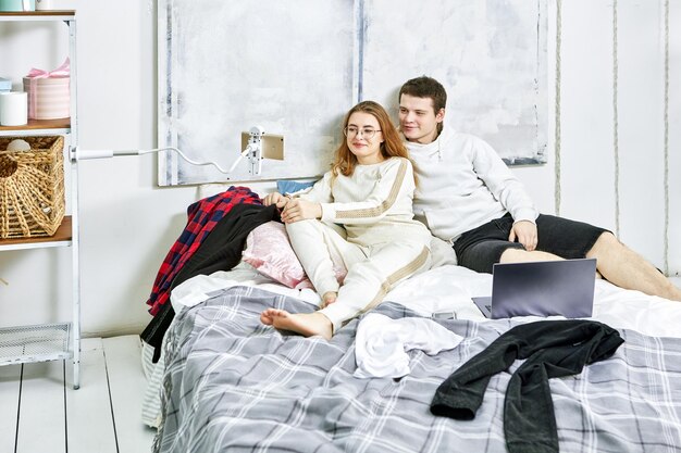 Zdjęcie portret uśmiechniętej pary siedzącej w łóżku w domu