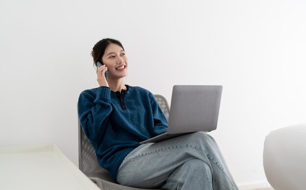 Portret uśmiechniętej pięknej biznesowej azjatyckiej kobiety korzystającej z laptopa i dzwoniącego do telefonu komórkowego z koncepcji domu