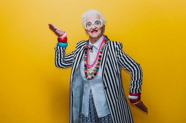 Zdjęcie portret uśmiechniętej starszej kobiety gestując na żółtym tle.