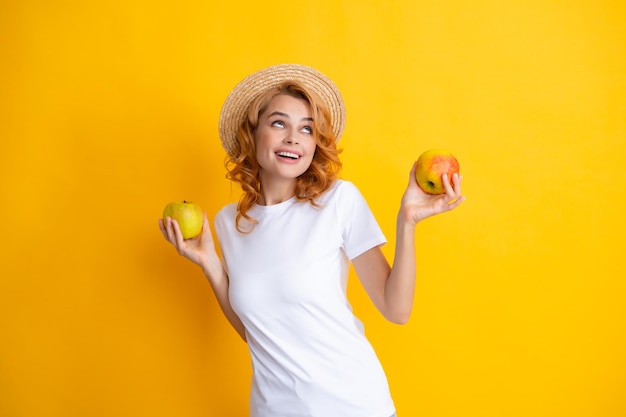 Portret uśmiechniętej szczęśliwej dziewczyny z jabłkiem odizolowanej na żółtym tle