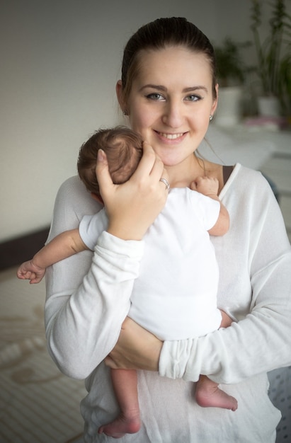 Zdjęcie portret uśmiechniętej troskliwej matki trzymającej na rękach słodkiego chłopca
