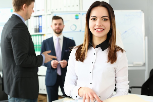 Portret uśmiechniętej ufnej biznesowej kobiety stojącej w biurze z kolegami w tle