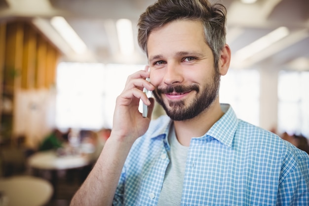 Portret uśmiechnięty biznesmen używa telefon w bufecie