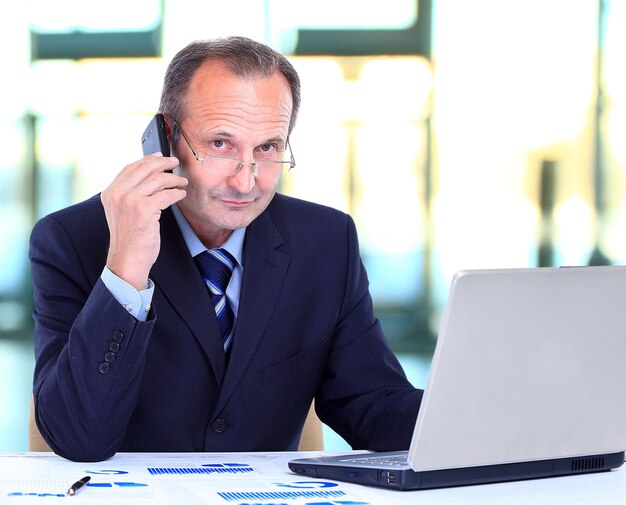 Portret Uśmiechnięty Człowiek Biznesu Rozmawia Przez Telefon Komórkowy I Pracuje Na Laptopie W Biurze