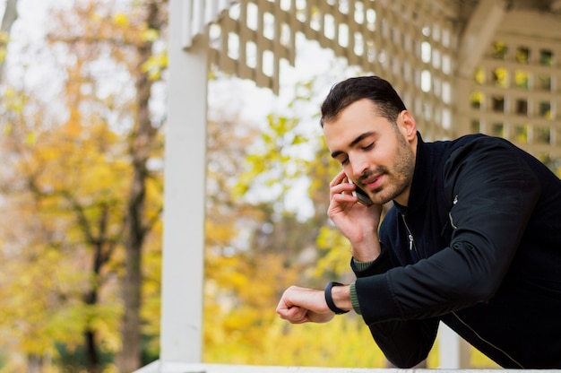 Portret uśmiechnięty facet opowiada na telefonie komórkowym outside.