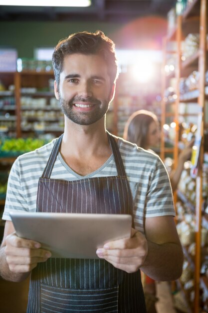 Portret uśmiechnięty męski personel używa cyfrową pastylkę w organicznie sekci