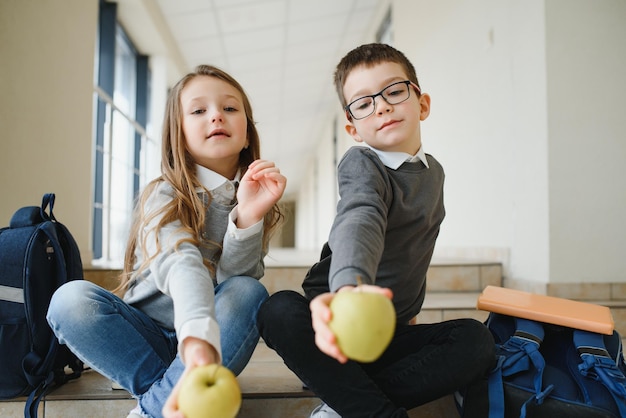 Portret uśmiechniętych dzieci w wieku szkolnym w szkolnym korytarzu z książkami