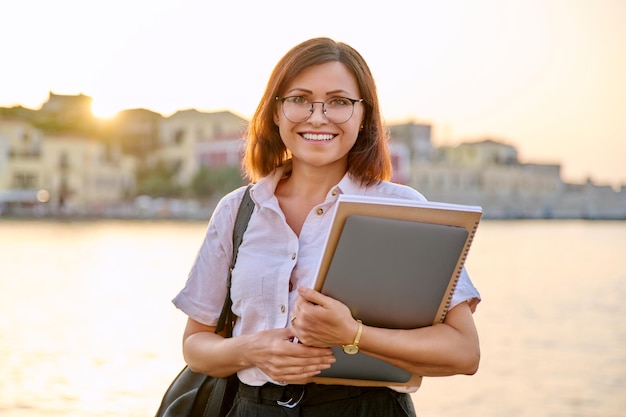 Portret w średnim wieku bizneswoman z laptopem w ręce patrzeje w aparacie