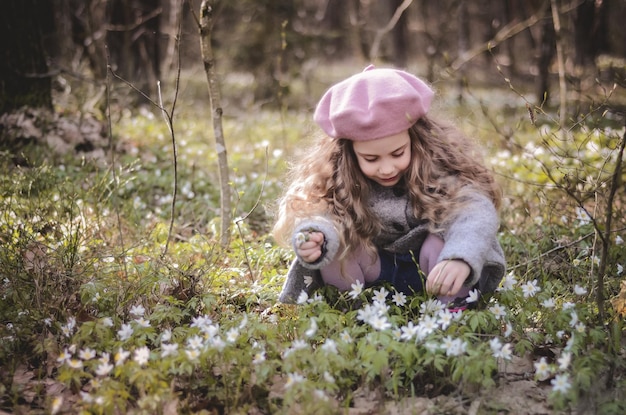Portret w stylu vintage ubrana mała dziewczynka bawiąca się w lesie