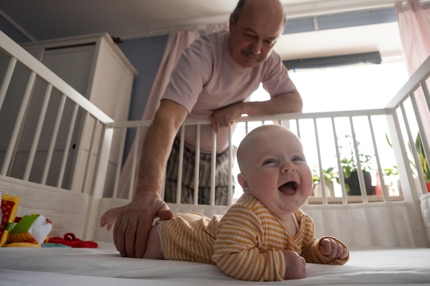 Portret wesołego dojrzałego dziadka bawiącego się z wnukiem w sypialni