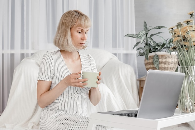 Portret wesołej kobiety w domu z laptopem podłączonym online do spotkania z przyjaciółmi Młoda kobieta pracująca z domowego biura Freelancer korzystający z laptopa i Internetu