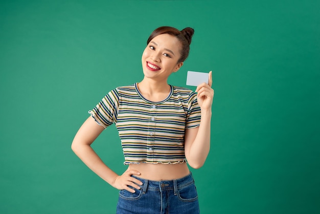 Portret wesołej młodej kobiety Azji pokazując kartę kredytową na zielono.