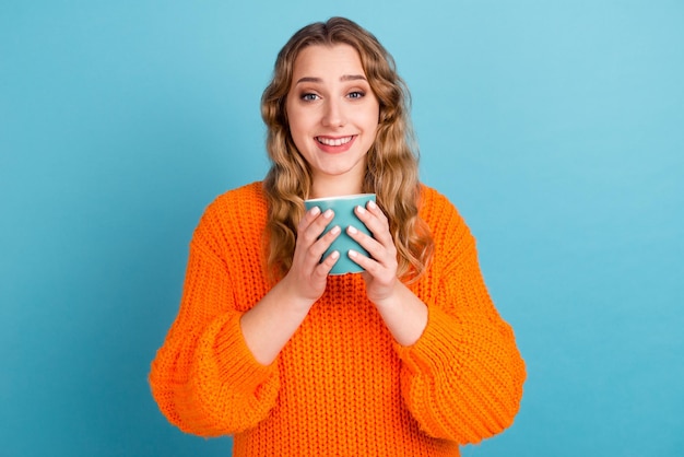 Portret wesołej śmiesznej młodej kobiety trzymaj filiżankę kawy i herbaty odizolowanej na niebieskim tle studio