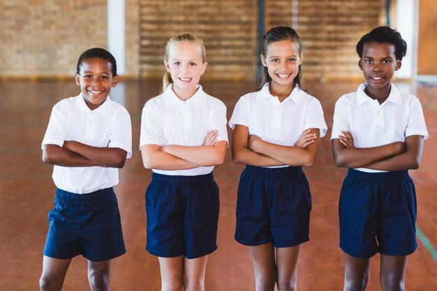 Portret wieloetnicznego dzieci w szkole stojącej z rękami skrzyżowanymi