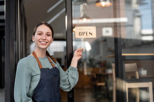 Portret właściciela kawiarni barista kobieta Mały przedsiębiorca z otwartym znakiem