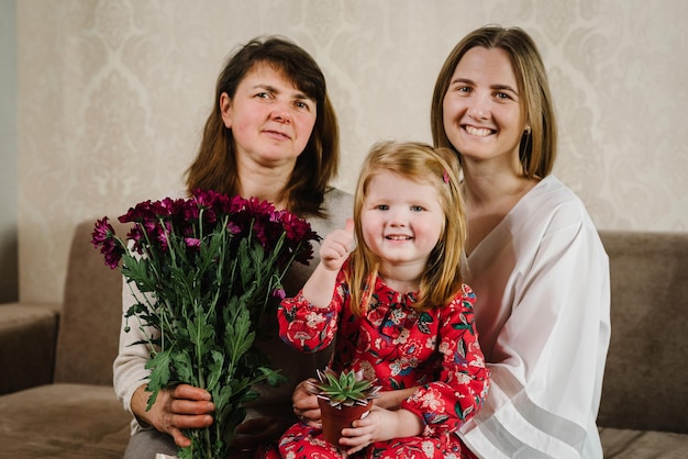 Portret wnuczka matka przytulająca babcia siedzi na kanapie w domu uśmiechając się i spędzając razem czas Międzynarodowy Dzień Kobiet Szczęśliwy Dzień Matki Koncepcja wakacji Trzy pokolenia kobiet