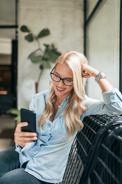 Portret wspaniała uśmiechnięta blondynki kobieta używa smartphone.