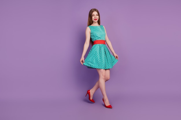 Portret wspaniałej pani spacerującej trzymaj krótką spódniczkę nosić mini sukienkę na wysokim obcasie na fioletowym tle