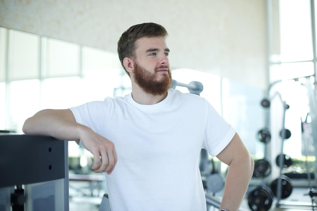 Portret wysportowanego młodego brodatego mężczyzny w trenerze fitness trenera