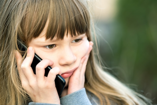 Portret Zaakcentowana Dziecko Dziewczyna Opowiada Na Telefonie Komórkowym Z Długie Włosy. Mały żeński Dzieciak Komunikuje Się Używać Smartphone. Koncepcja Komunikacji Dzieci.