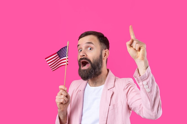 Portret zadowolonego młodzieńca z brodą z amerykańską flagą na czerwonym tle studia Wielki patriota USA i obrońca wolności