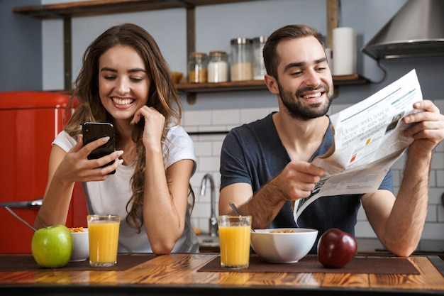 Portret zadowolony para mężczyzna i kobieta siedzi przy stole w kuchni jedząc śniadanie w domu w godzinach porannych