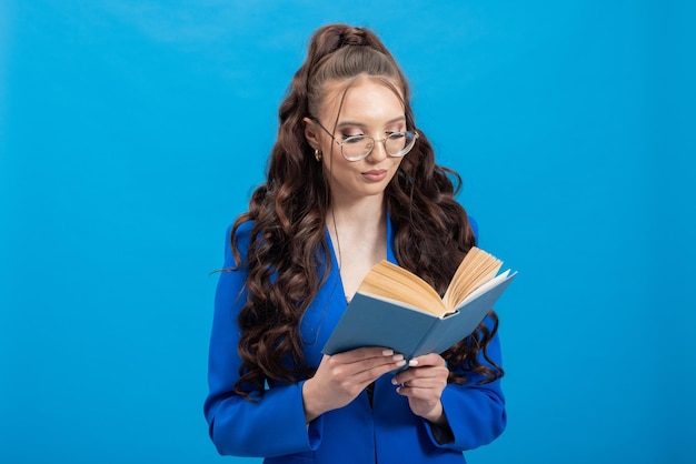 Portret zamyślonej, ambitnej kobiety w okularach, trzymającej książkę, którą czyta nauczyciel