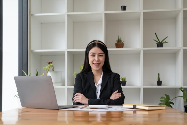 Portret zaufania azjatycka biznesowa kobieta patrząca na kamerę siedzącą przy biurku w biurze