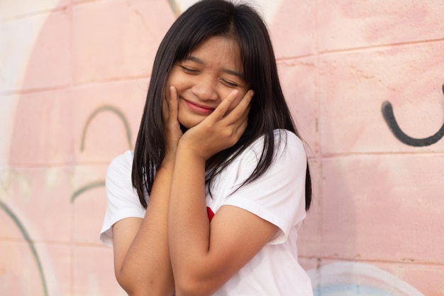 Portret zbliżenie twarzy Azjatycka młoda dziewczyna ma na sobie tshirt z sercem na kolorowym tle