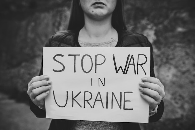 Portret zdenerwowana dziewczyna lub kobieta dzwoni Żadna wojna nie podnosi transparentu z napisem Stop wojnie na Ukrainie Pokój zatrzymaj rosyjską agresję Zjednoczona Europa przeciwko Rosji Nadzieja na świat Czarno-białe zdjęcie