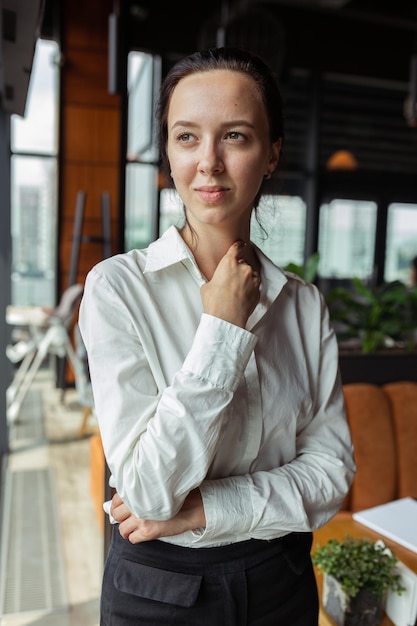 Portret zdeterminowanej bizneswoman noszącej formalną białą koszulę stojącą w kawiarni