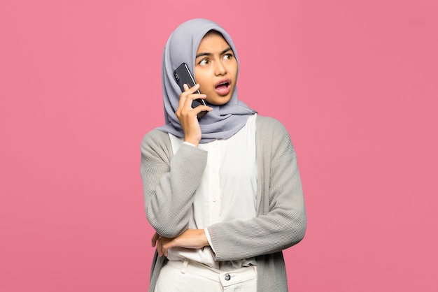 Portret zdumiony młoda kobieta Azji rozmawia z przyjaciółmi w telefonie komórkowym
