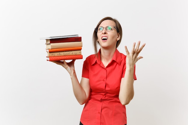 Portret zmęczonej sfrustrowany zdenerwowany nauczyciel biznesu kobiety w czerwonej koszuli okulary trzymając książki tekstowe stosu w rękach na białym tle. Edukacja lub nauczanie w koncepcji uniwersytetu liceum.