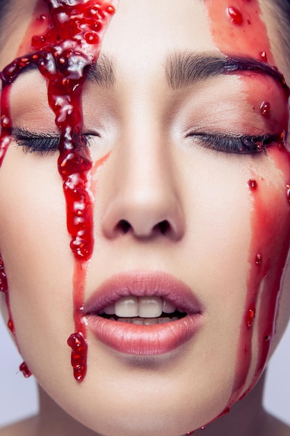Portret zmysłowej modelki z perfekcyjnym makijażem z czerwonym dżemem płynie po twarzy