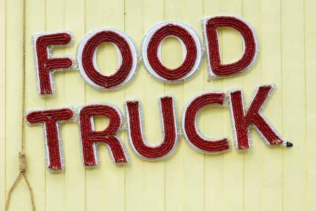 Portret znaku Food Truck z linami używanymi jako napis na żółtej drewnianej ścianie
