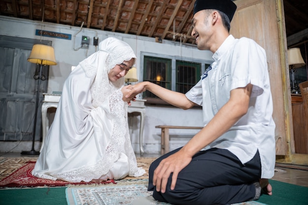 Portret żony całuje rękę męża po wspólnej modlitwie w domu. sholat lub salat