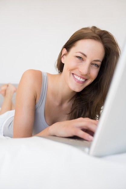Portret zrelaksowana kobieta używa laptop w łóżku