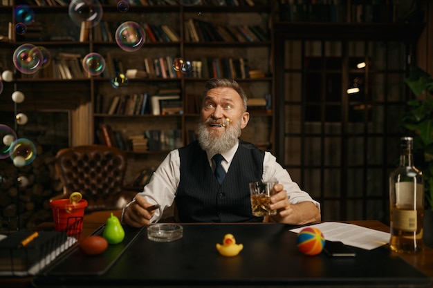 Portret zrelaksowanego starszego biznesmena palącego cygaro i pijącego whisky