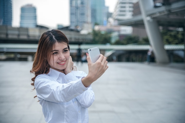 Portrety Ładna Piękna Azjatycka kobieta bierze fotografię selfie w miastowym.