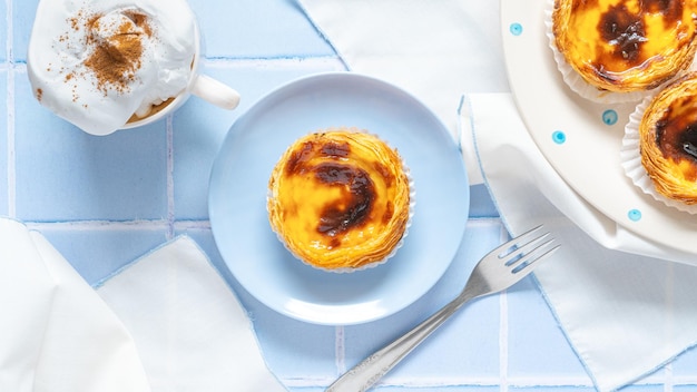 Portugalski deser Pastel de nata z kawą na niebieskiej płytce
