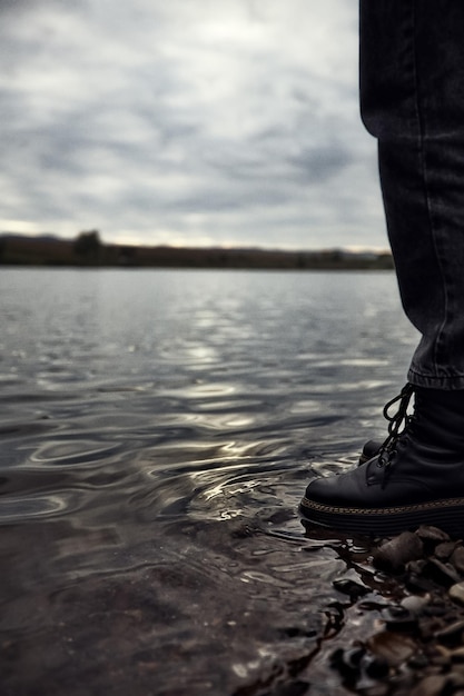 Porzucony nastolatek mężczyzna stojący nad wodą patrzy i zastanawia się nad ciężkim życiem butów w wodzie